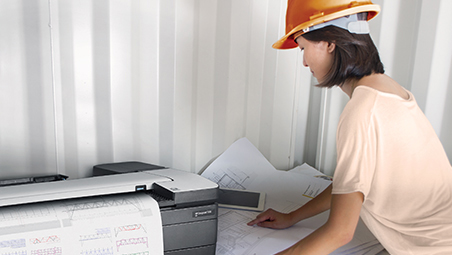 Construction worker in hard hat printing floor plans on HP DesignJet at job site