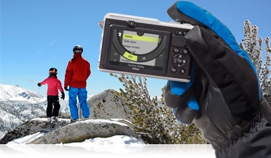 Photo of the Nikon 1 AW1 in a gloved hand with a parent and child in the background on a mountain
